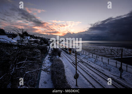 Treno nella neve. C2C convoglio ferroviario in esecuzione attraverso la coperta di neve linee in Chalkwell vicino a Southend on Sea, Essex all'alba accanto all'estuario del Tamigi Foto Stock