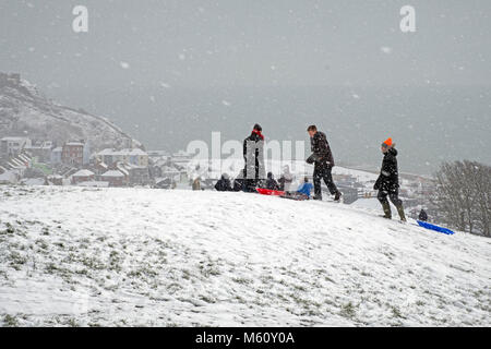 Hastings, Winter, East Sussex, UK, 27 Feb 2018. Le famiglie si divertono nella neve su West Hill, con Hastings Old Town nella valle e la neve coperta East Hill Beyond. Foto Stock