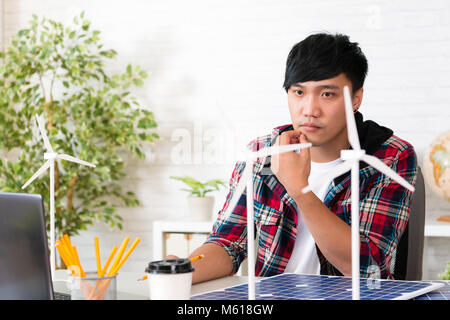 Uomo asiatico il potere di vento tecnico che cerca il pensiero di mulino a vento ispirazione nuova idea di energia alternativa in studio office Foto Stock