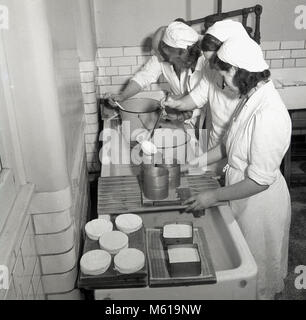 Degli anni Cinquanta, foto storiche che mostra tre giovani femmine agricolo di studenti all'interno di un caseificio la produzione di formaggio. Tale esperienza pratica per apprendere nuove abilità e di approfittare delle opportunità nel settore agricolo nel post-conflitto in Gran Bretagna è stato incoraggiato attivamente, come vi è stata una necessità e una grande domanda per saperne di più home-coltivate alimentari. Foto Stock