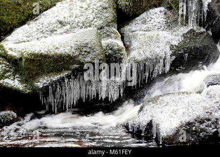 Ghiaccioli sulle rocce al fiume Glencree vicino a Enniskerry, come la nevicata colpisce le strade di tutto il Regno Unito dopo parecchi centimetri cadde in alcune parti per tutta la notte. Foto Stock