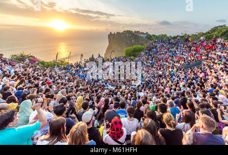 I turisti a guardare il tramonto con uno stile Balinese tradizionale danza Kecak al Tempio di Uluwatu di Bali Indonesia. Foto Stock