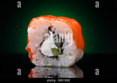 Un rullo con pesce rosso e il cetriolo su uno sfondo nero. Il ristorante giapponese e menu, close-up Foto Stock