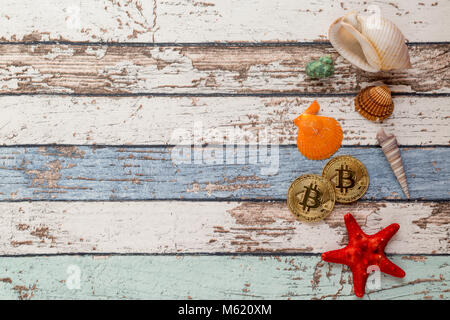 Due golden bitcoins con conchiglie e stelle marine su vintage tavolo in legno vista superiore Foto Stock