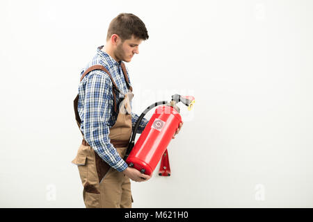 Giovane tecnico che esegue Red estintore contro uno sfondo bianco Foto Stock