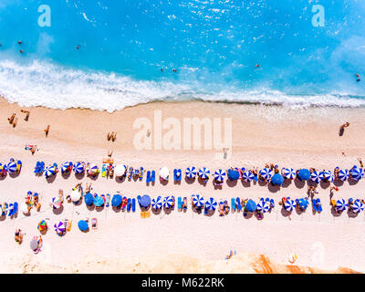 Vista dall'alto in basso di una spiaggia con i turisti suntbeds e ombrelloni con spiaggia di sabbia e acque cristalline in Grecia Foto Stock