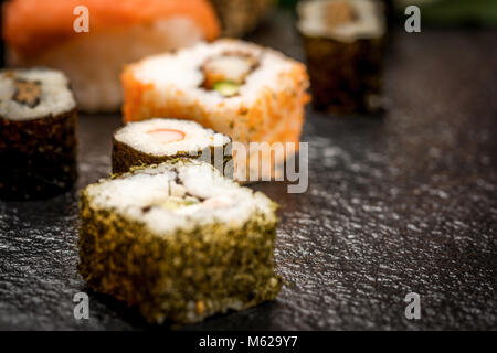 Il sushi tradizionale giapponese rotoli hosomaki,uramaki sul banco di pietra Foto Stock