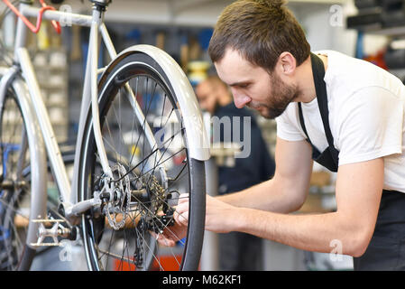 Amichevole e competente e meccanico di bicicletta in una riparazione in officina una bici Foto Stock