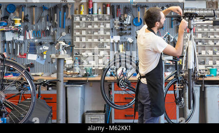 Amichevole e competente e meccanico di bicicletta in una riparazione in officina una bici Foto Stock