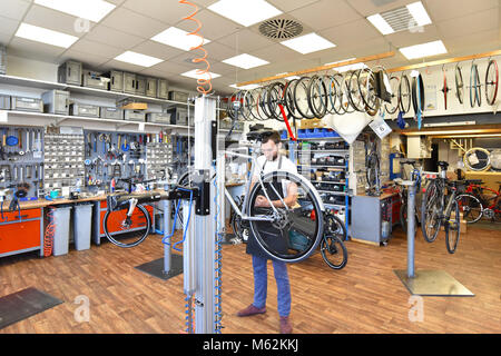 Amichevole e competente e meccanico di bicicletta in una riparazione in officina una bici Foto Stock