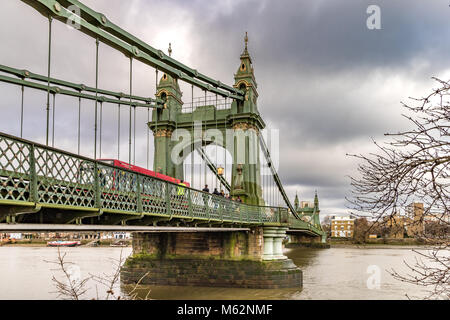 Un single decker Bus londinese attraversa Hammersmith Bridge sul fiume Tamigi , Hammersmith , Londra Foto Stock