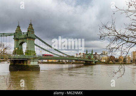 Un single decker Bus londinese attraversa Hammersmith Bridge sul fiume Tamigi , Hammersmith , Londra Foto Stock