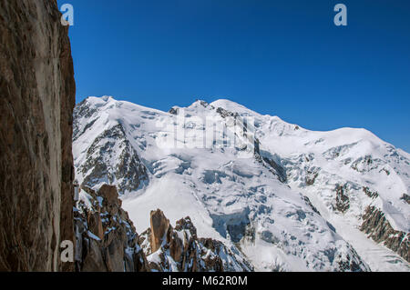 Snowy Mont Blanc e rocce, visto dall'Aiguille du Midi, vicino a Chamonix. Una famosa stazione sciistica ai piedi del Mont Blanc nelle Alpi francesi. Foto Stock