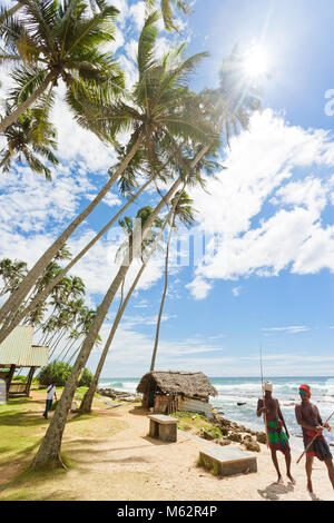 Koggala Beach, Sri Lanka, Asia - Dicembre 2015 - Due pescatori nativi per raggiungere a piedi la spiaggia per andare a pesca Foto Stock