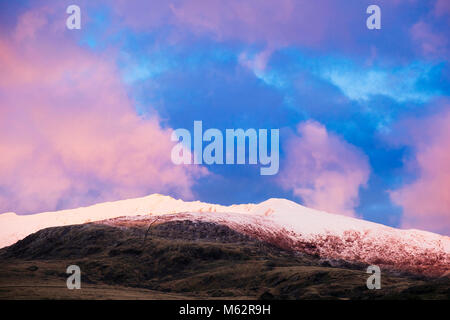 Nuvole rosa al tramonto sopra Snow capped Mt Snowdon e la cresta sud in inverno nelle montagne del Parco Nazionale di Snowdonia da Rhyd Ddu Gwynedd Wales UK Foto Stock