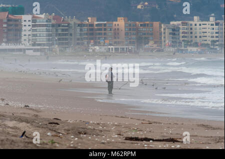 Un solitario pescatori sulla spiaggia. La Serena in background e uccelli. Foto Stock