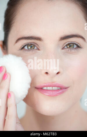 Donna con polvere puff a faccia Foto Stock