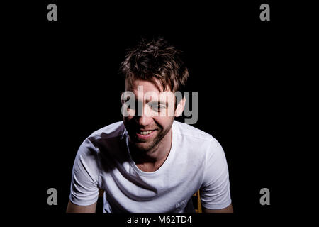 Bianco maschio europeo shot in studio sorridente e guardando verso il basso, felici e rilassati Foto Stock