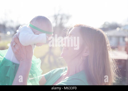 Donna che mantiene baby fino all'esterno in condizioni di luce solare intensa - sovraesposte per effetto Foto Stock