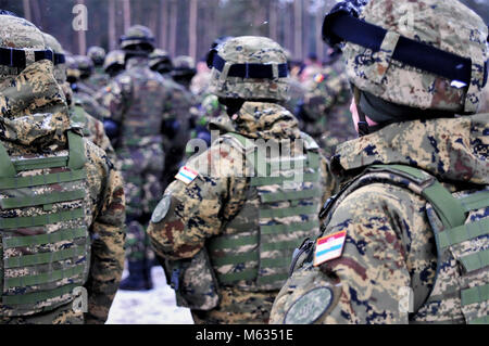 Soldati croati, assegnato alla batteria di Vulcano e Battle Group Polonia stand in formazione durante la cerimonia di apertura per l'inizio dell'esercizio il Puma, un esercizio il test delle funzioni di interoperabilità del Battle Group della Polonia e la sua sede centrale superiore, la XV Brigata meccanizzata, vicino Bemowo Piskie Area Formazione, Polonia nel febbraio 12, 2018. Gruppo di combattimento della Polonia è un luogo unico e multinazionali del Battle Group, composta di Stati Uniti, Regno Unito, croato e soldati rumeni che servono con il polacco della XV Brigata meccanizzata come una forza di dissuasione nel nord-est della Polonia a sostegno della NATO in avanti Enhanced P Foto Stock