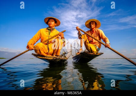 Due pescatori, seduti sulle loro barche paddeling, sono la pesca in modo tradizionale sul Lago Inle Foto Stock
