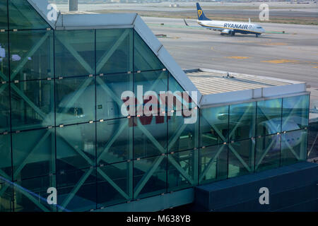 Il piano si riflette in una costruzione terminale mentre un altro aereo di linea taxi passato, Aeroporto di Barcellona Foto Stock