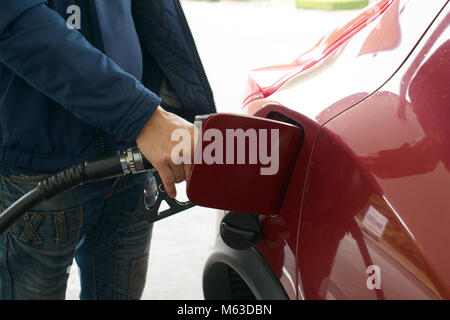 Un uomo di pompaggio o mettere benzina in un auto presso la stazione di gas. Foto Stock