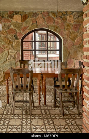 Interno rustico in pietra con tavoli e sedie in legno. Interni del ristorante Vintage con un'accogliente sala da pranzo ad angolo. Foto Stock