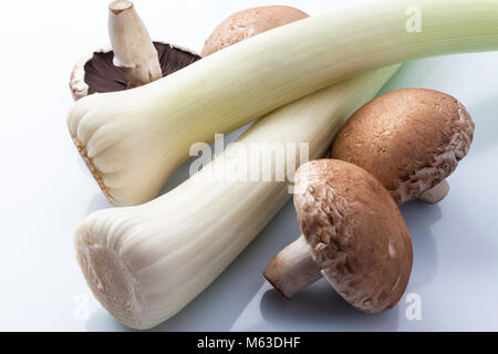 Il Porro e grandi funghi marrone su sfondo bianco dal di sopra Foto Stock