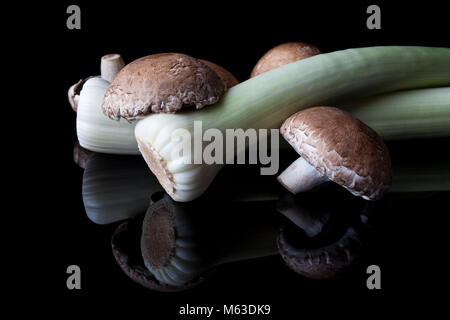 Il Porro e grandi funghi marrone su sfondo nero Foto Stock