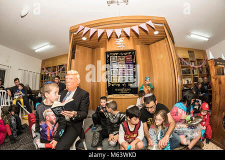 Elkana, Israele. 28 Feb, 2018. Purim holiday celebrazioni, Elkana, Israele. Febbraio 28th, 2018. Un uomo con una maschera di briscola e altri personaggi in costume celebrare la festa ebraica di Purim. In questa vacanza ebrei traditionaly vestito in costumi, leggere la chiocciola di Esther, una storia su un anti-ebraica complotto fallito nell antica Persia e fare un racket ogni volta che il nome di Haman, l'antagonista principale, è menzionato. Credito: Yagil Henkin/Alamy Live News Foto Stock