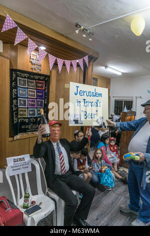 Elkana, Israele. 28 Feb, 2018. Purim holiday celebrazioni, Elkana, Israele. Febbraio 28th, 2018. Un uomo con una maschera di briscola e altri personaggi in costume celebrare la festa ebraica di Purim. (Lo slogan "Gerusalemme è Israele la "birra" è un gioco di parole sulla parola ebraica per la capitale, 'Beera'). In questa vacanza ebrei traditionaly vestito in costumi, leggere la chiocciola di Esther, una storia su un anti-ebraica complotto fallito nell antica Persia e fare un racket ogni volta che il nome di Haman, l'antagonista principale, è menzionato. Credito: Yagil Henkin/Alamy Live News Foto Stock