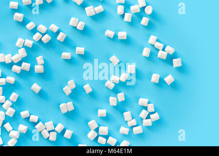 Marshmallows su sfondo blu con copyspace. Appartamento laici o vista dall'alto. Lo sfondo o la texture di coloratissimi mini marshmallows. Inverno sfondo alimentare conc Foto Stock