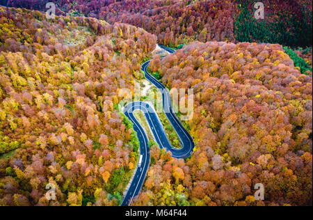 Tortuosa strada attraverso la foresta. Hi mountain pass in Transilvania, Romania. Vista aerea da un drone. Foto Stock