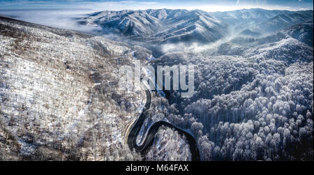 Panoramica di immagini di una tortuosa strada da un high mountain pass in Transilvania in inverno con sn da montagne coperte di visibile nella parte posteriore Foto Stock