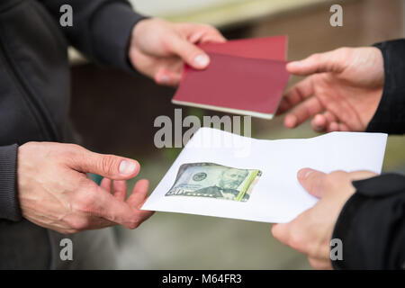 Mano umana dando la banconota e acquisto illegale di passaporto straniero Foto Stock