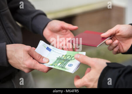 Mano umana dando la banconota e acquisto illegale di passaporto straniero Foto Stock