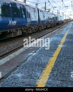 Close up ScotRail locale treno dei pendolari a Drem stazione ferroviaria in inverno con sale sulla piattaforma della stazione, East Lothian, Scozia, Regno Unito Foto Stock