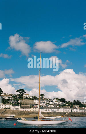 Flottante in barca nel porto di St Mawes, Cornwall, Inghilterra. Navigare in appoggio in acque calme con la vista della parte in blu cielo con alcune nuvole Foto Stock