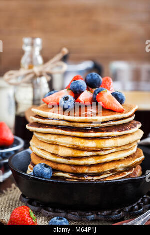 Pila di preparati di fresco frittelle di banana con frutti di bosco freschi e sciroppo d'acero per la prima colazione Foto Stock