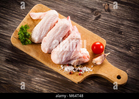 Materie di ali di pollo sul tagliere sul tavolo di legno Foto Stock