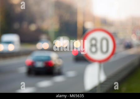 Immagine sfocati del segnale di limite di velocità con un traffico in background su una autostrada Foto Stock