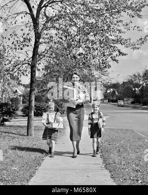 Anni Cinquanta la madre di due figli che camminano giù autunno marciapiede suburbana che trasportano i pacchetti SHOPPING GUARDANDO TELECAMERA - J2439 HAR001 HARS vecchio tempo fratello OLD FASHION SORELLA 1 capretti stile figli caucasica lieta gioia LIFESTYLE FEMMINE FRATELLI HOME VITA spazio copia a lunghezza piena figlie Cari fratelli sorelle fiducia nostalgia stare insieme il contatto visivo 3-4 anni 5-6 anni quartiere allegro mamme gemelli sorride gioiosa piccolo gruppo di persone giovani maschi MID-adulto metà donna adulta confezioni B&W in bianco e nero di etnia caucasica guardando la fotocamera in vecchio stile persone Foto Stock