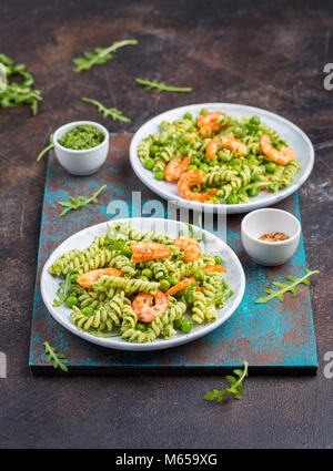 Una sana insalata di pasta con gamberetti, piselli verdi e foglie di rucola Foto Stock