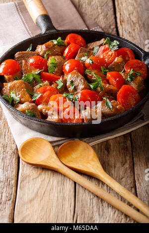 Di vitello in salsa piccante con pomodorini e verdi di close-up in una padella verticale. Foto Stock