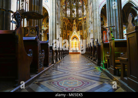 Lungo le corsie fra le file di banchi di golden statue dietro altera in magnifica Chiesa votiva di Vienna. Foto Stock
