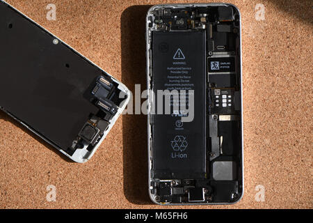 Home DIY la sostituzione di un iPhone 5s batteria che mostra telefono aperto con la nuova e la vecchia batteria e gli elementi interni del telefono. Foto Stock