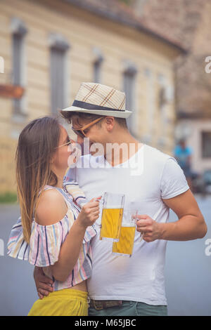 Giovani hipster matura in amore il tifo con boccali da birra presso la strada di città Foto Stock