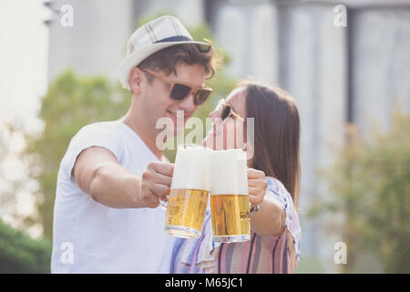 Giovani hipster matura in amore il tifo con boccali da birra presso la strada di città Foto Stock