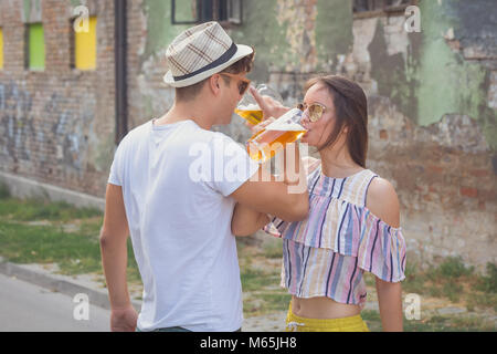 Coppia giovane a bere birra con due mani incrociate sulla strada Foto Stock